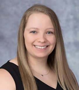 Headshot of Abby Farrell. She is a Caucasian woman smiling. She has long blonde hair and blue eyes. She is wearing a black tank top and silver pendant necklace